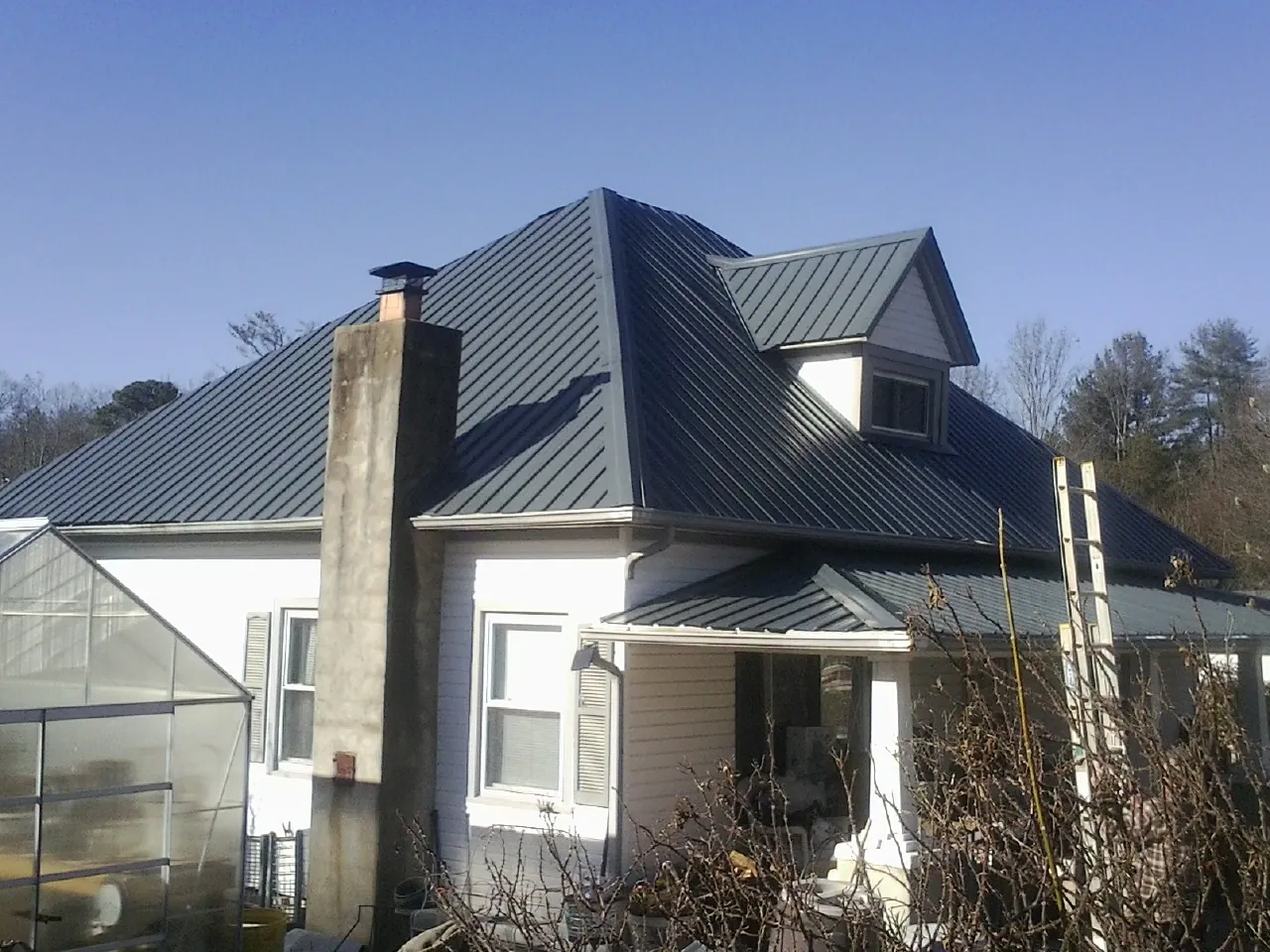 Dark blue standing seam metal roof on a white farmhouse with dormer in East Brookfield
