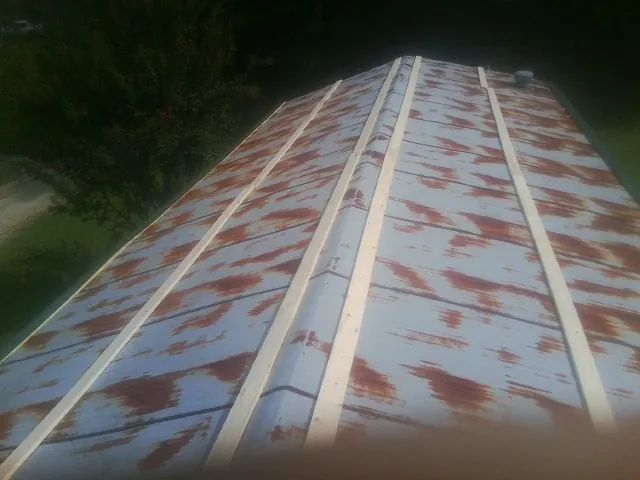 Rusted metal roof panels with new wood purlins before replacement — Storm Damage Roof Repair in East Brookfield by Roofing Brothers