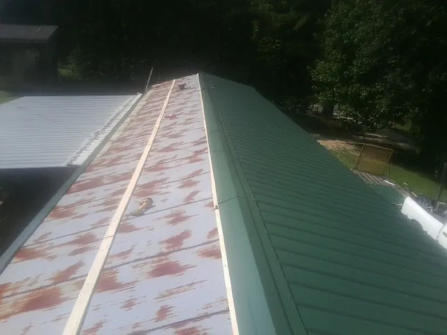 Old rusted panels beside newly installed green metal roofing — Wind Damage Roof Repair by Roofing Brothers in East Brookfield