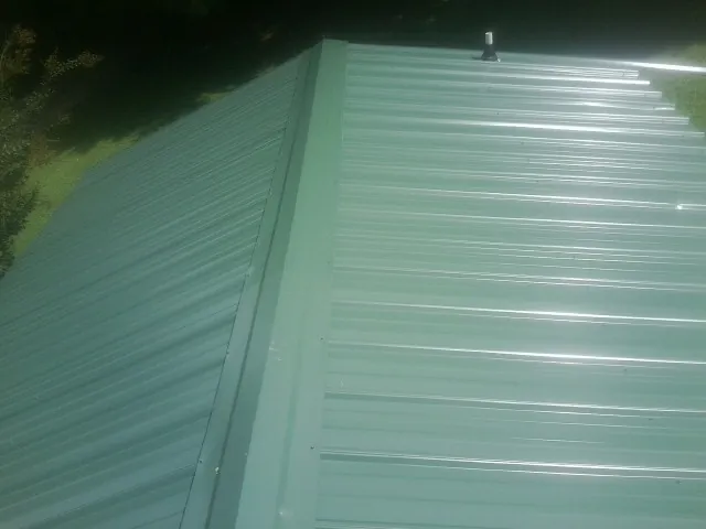New green metal panels meeting at the ridge of a roof — Flat Roof Repair work by our crew in East Brookfield