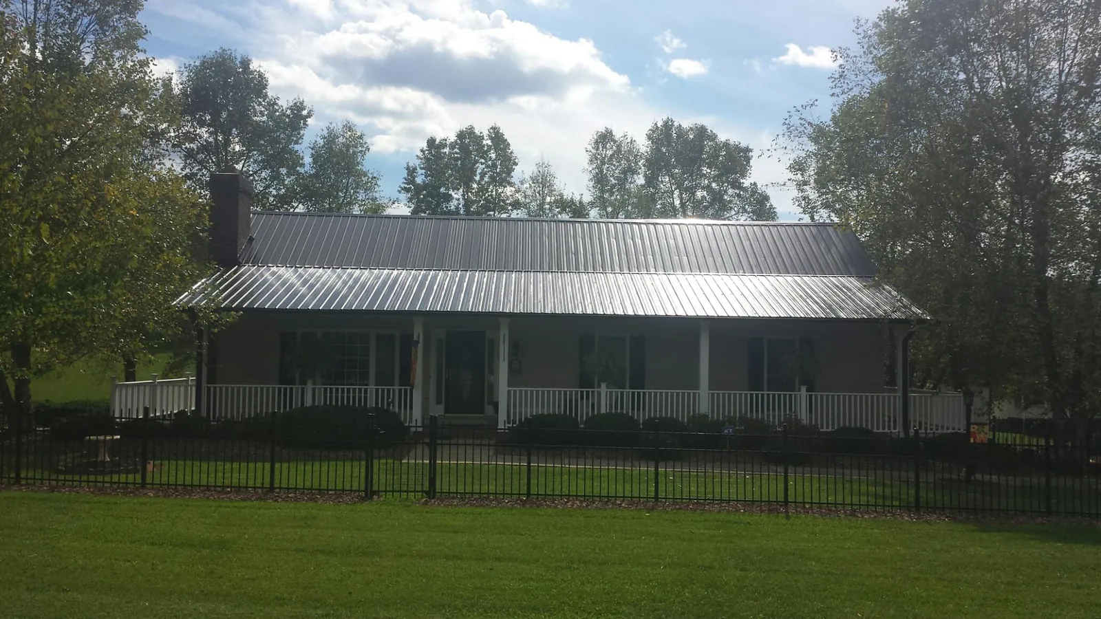 Gray metal roof on a brick ranch with a full width front porch — Gutter Guard Installation work by our crew in East Brookfield