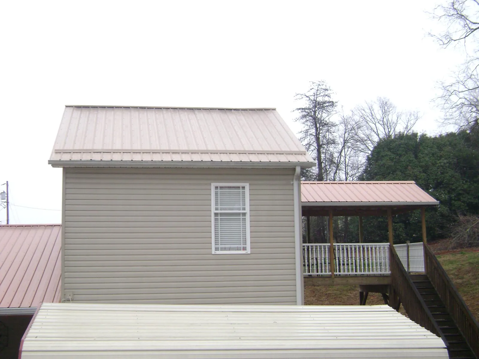 Tan metal roofs on a two story addition and attached porch, from a Roof Replacement job in East Brookfield
