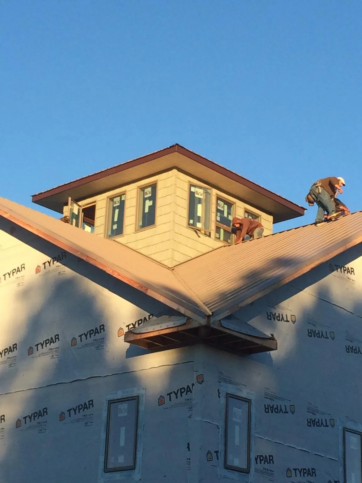Roofers working around a rooftop cupola on a new metal roof at sunset — Roof Waterproofing in East Brookfield by Roofing Brothers